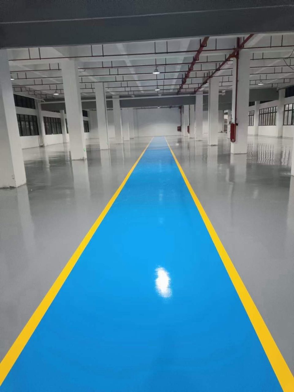 厂房车间环氧地坪施工实拍——环氧自流平,厂房车间内部地面施工完成场景,灰色环氧自流平地面规整,蓝色通道搭配黄色边线,空间