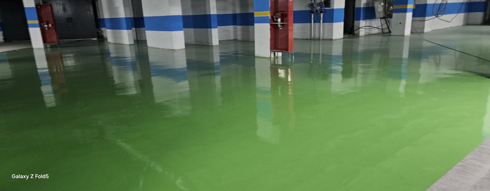 地下车库环氧地坪完工：绿色停车位与柱体防撞色带
