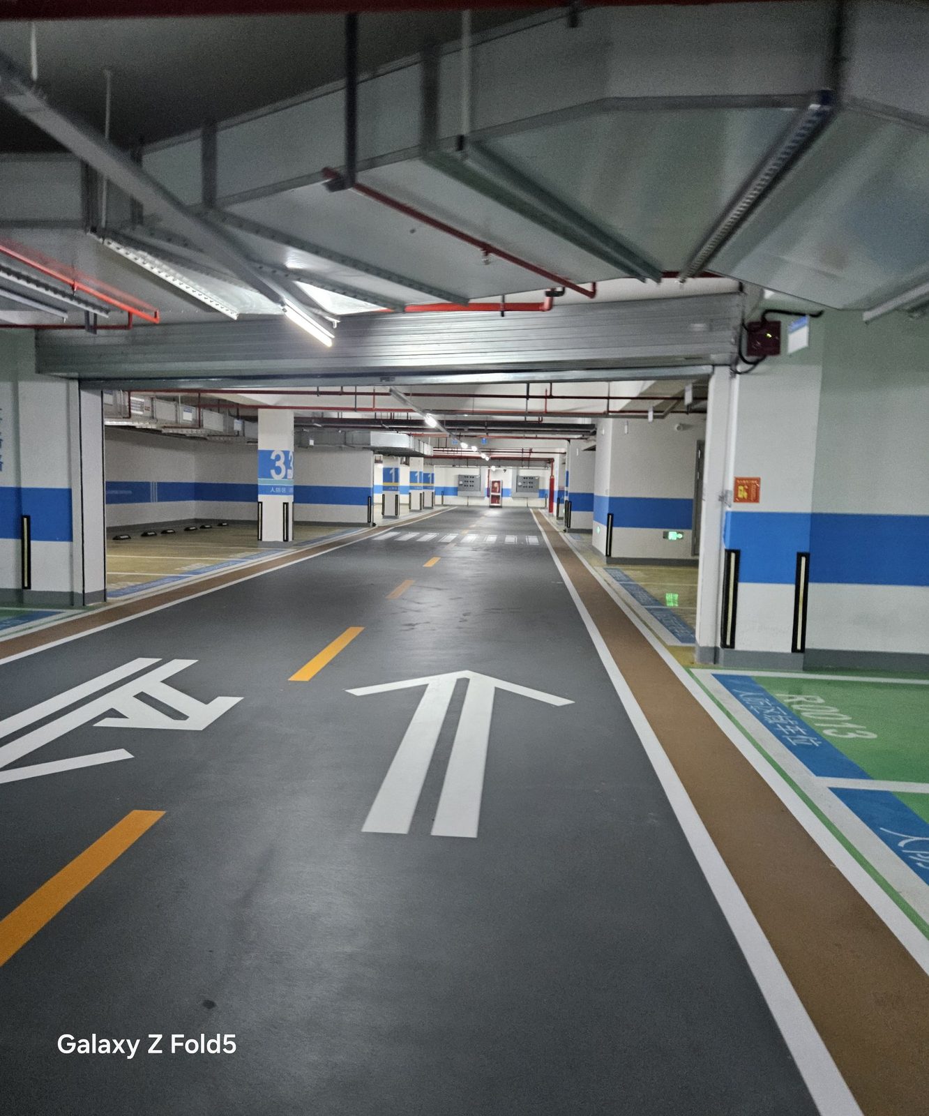 蓝城·云晟府地下车库：人防区行车道另一视角，导向箭头与柱面标识带