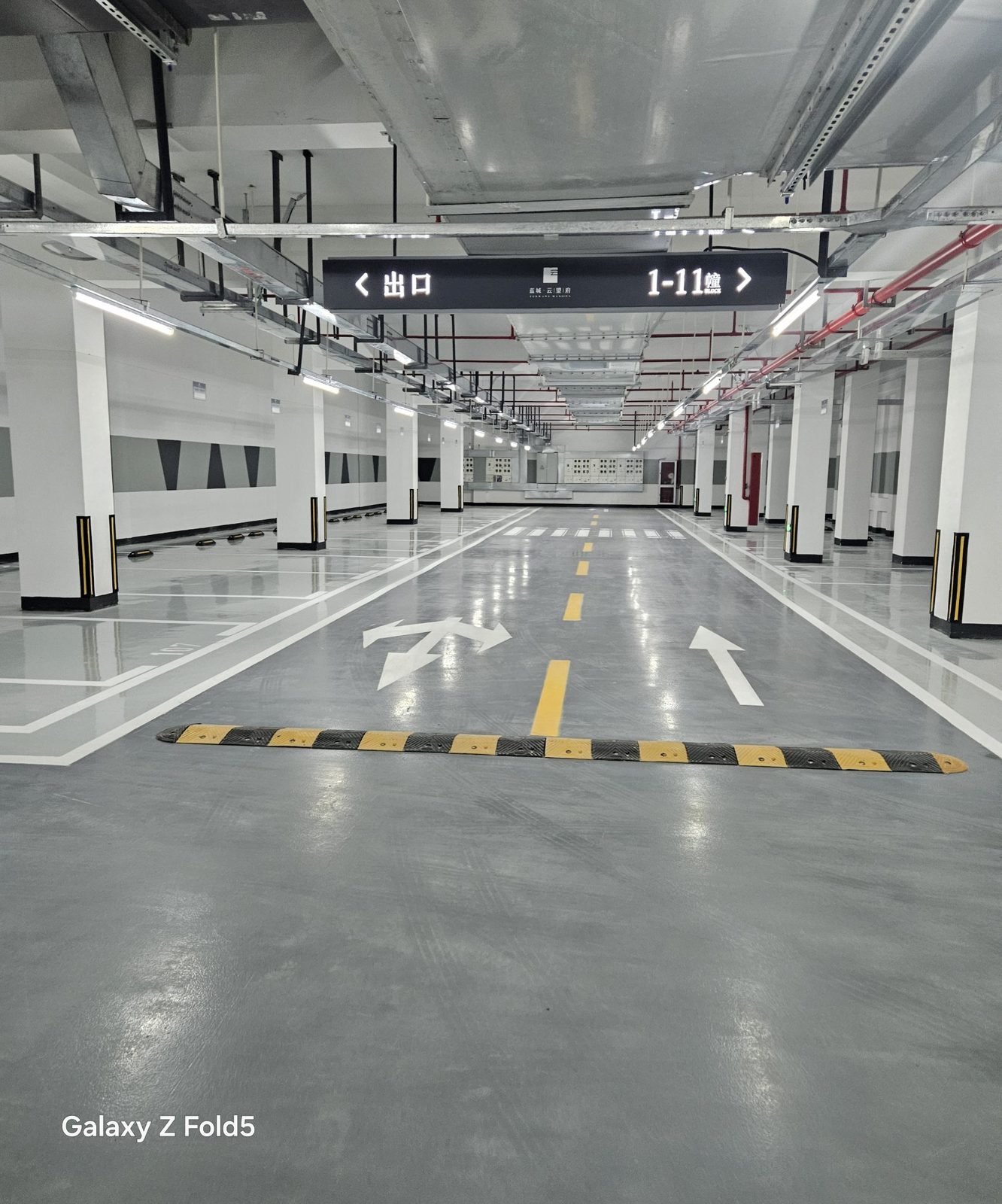 蓝城·云晟府地下车库：悬挂指示牌出口1-11幢，减速带与灰色环氧行车道