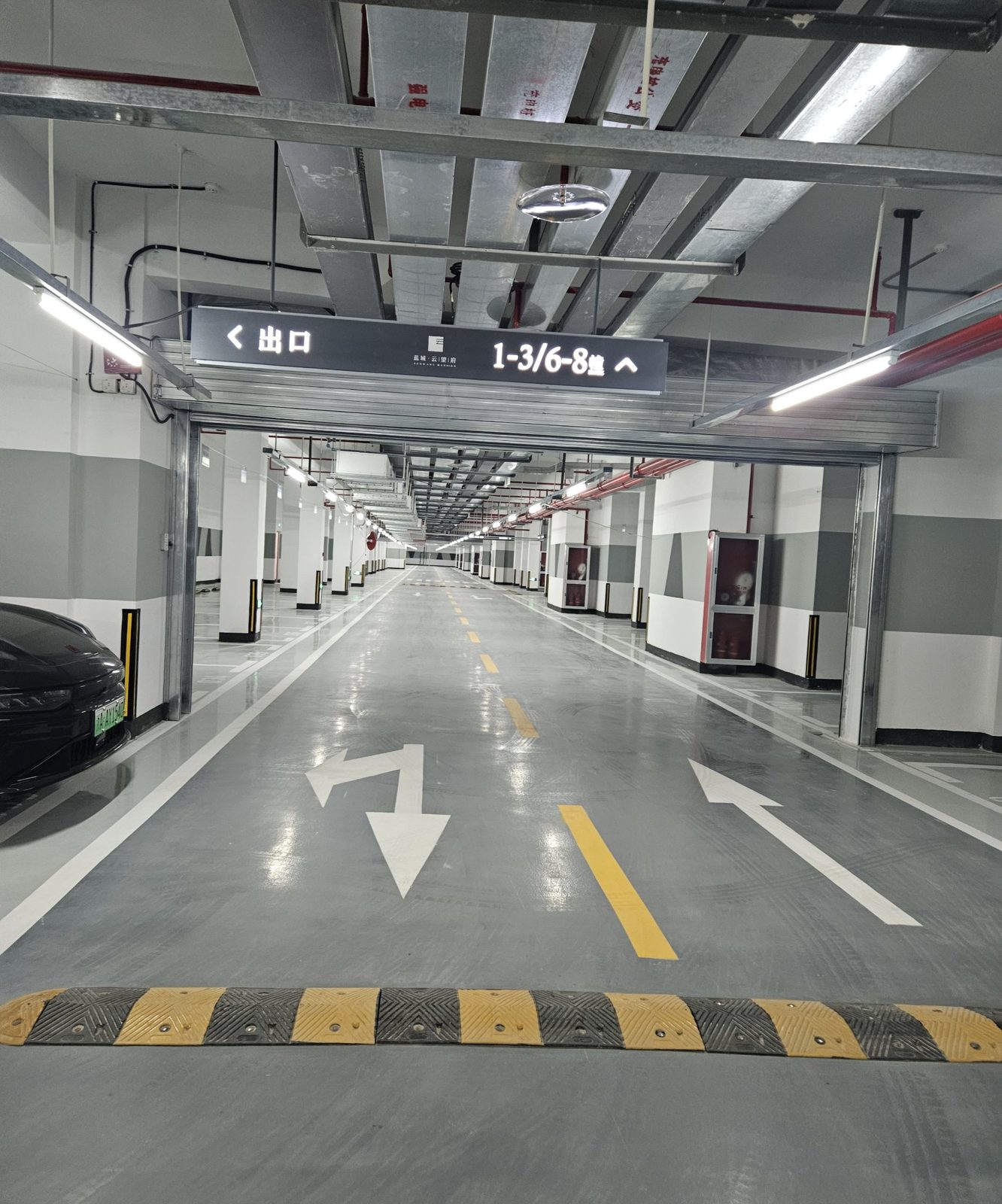 蓝城·云晟府地下车库：悬挂指示牌出口1-3/6-8幢，减速带与灰色环氧行车道