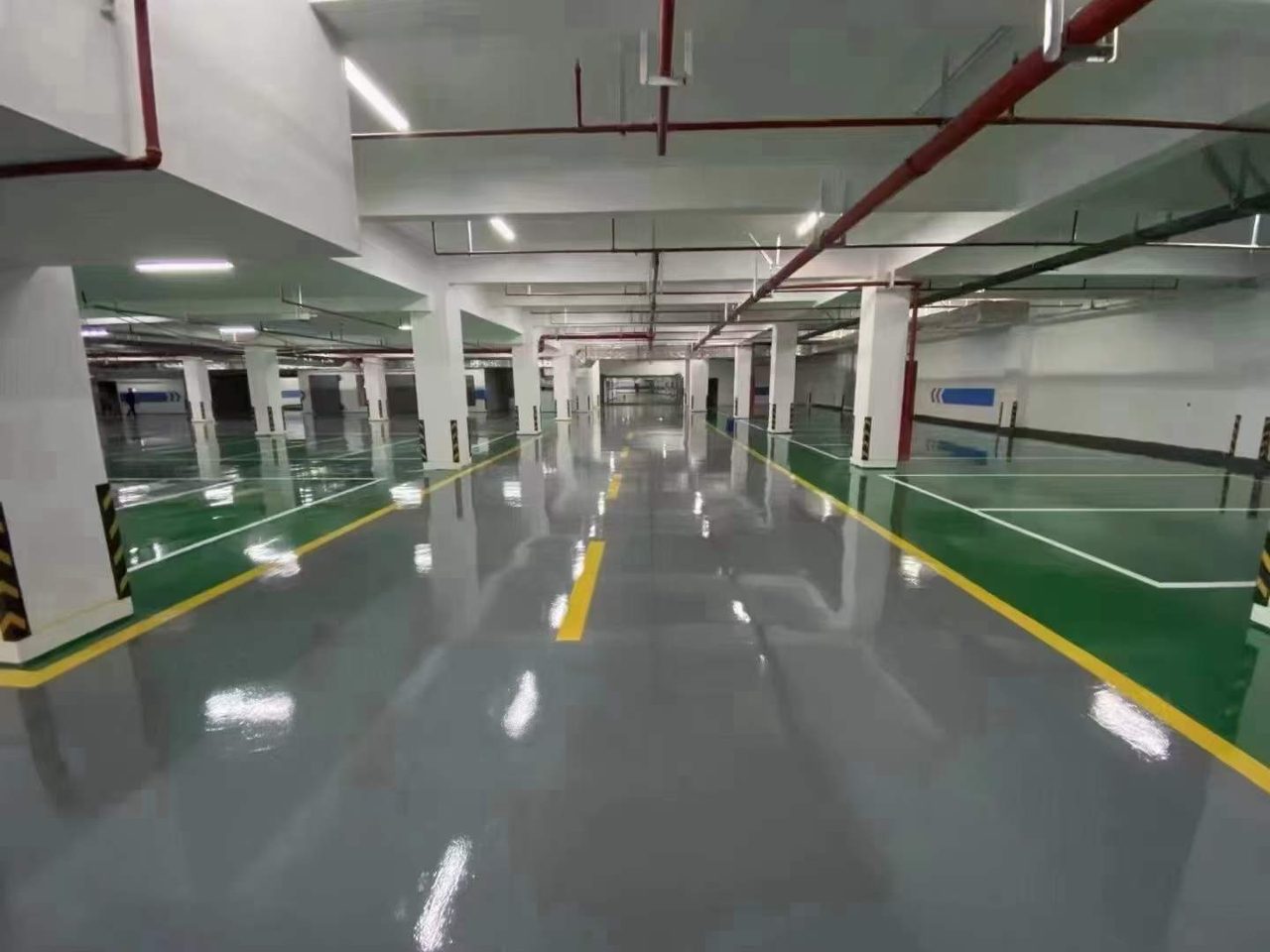 地下车库环氧地坪施工实拍——环氧自流平，镜面反光平整的地下车库环氧地坪行车区域，设置柱体与行车标线